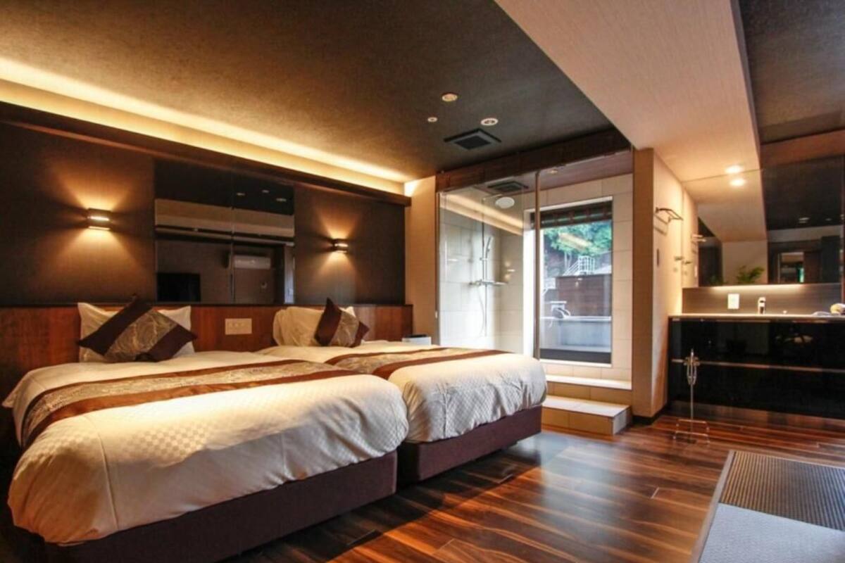 Ein modernes Hotelzimmer mit einem großen Bett, einer kleinen Küchenzeile und Blick ins Freie.