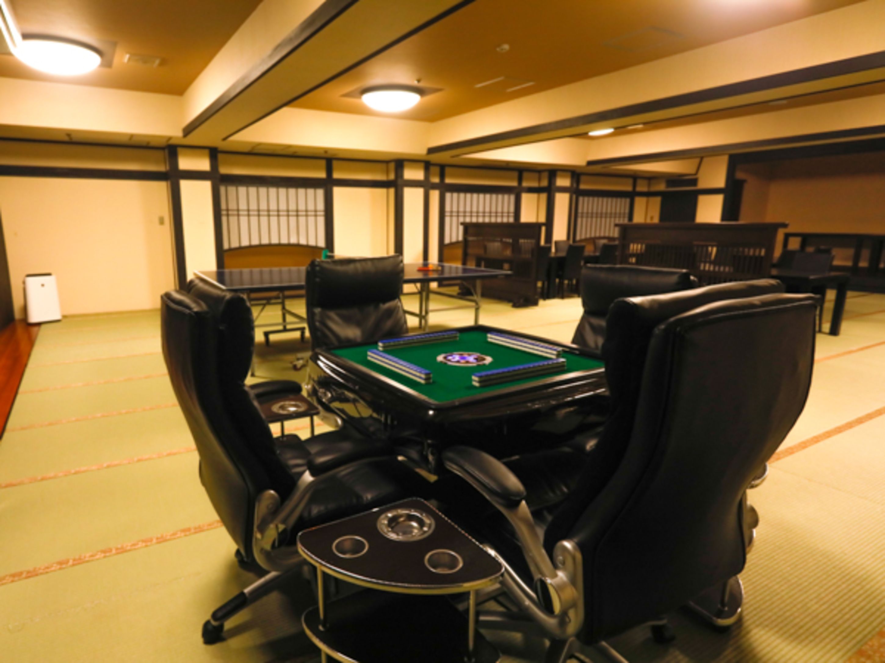 A room with a pool table, leather chairs, and a small table with a lamp.