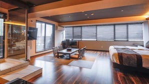 A modern hotel room with a large bed, a dining area with a table and chairs, and a glass shower enclosure. - LiVEMAX RESORT AKIMIYAJIMA (Hatsukaichi)