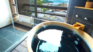 A modern bathroom with a glass-enclosed shower, a bathtub, and a view of a town and mountains. - LiVEMAX RESORT AKIMIYAJIMA (Hatsukaichi)