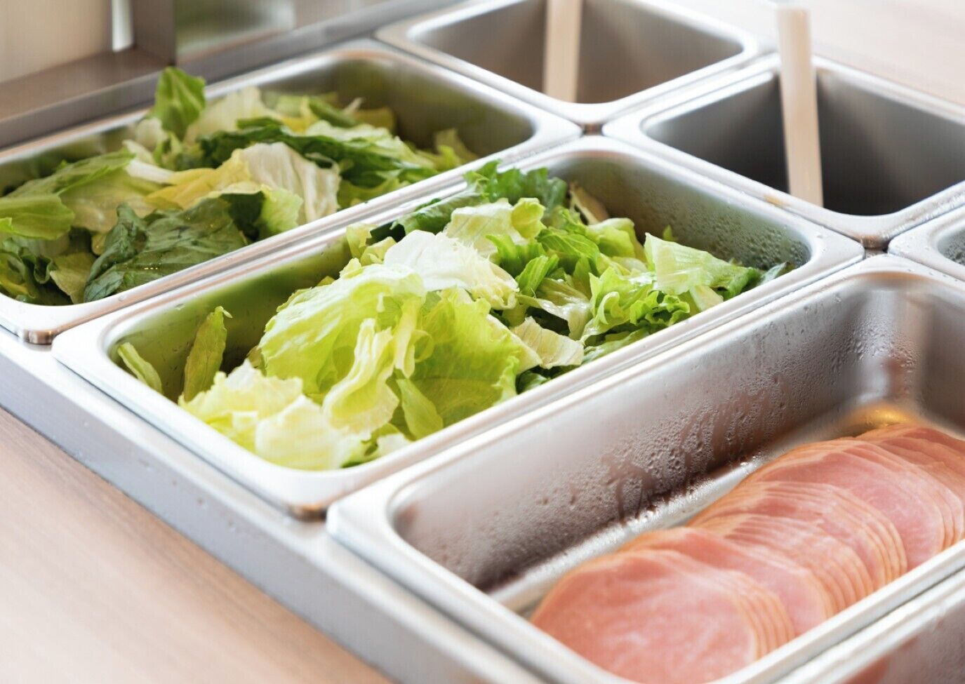 A buffet with various food options including greens and sliced meat.