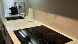 A modern kitchen with a black induction cooktop, a coffee maker, and a paper towel holder.