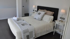 A neatly made bed with a white and gray patterned blanket, two bedside lamps, and a small bedside table with a book.
