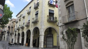 A row of yellow buildings with arched doorways, a sign for 'Chafoca' on the ground floor, and balconies with plants.