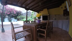 Eine Terrasse im Freien mit einem Holztisch und -stühlen, einem Blumentopf und einem gefliesten Boden.
