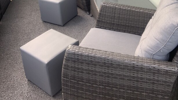 A balcony with wicker furniture, including two chairs and two ottomans, and a glass table. - Modern furnished, 80 m² 3-room apartment with south / west-facing balcony (Goldkronach)