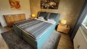 A bedroom with a bed, bedside tables, a nightstand, a dresser, and artwork on the walls. - Modern furnished, 80 m² 3-room apartment with south / west-facing balcony (Goldkronach)