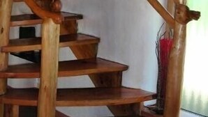 A wooden staircase with a rustic design, featuring a handrail and steps made of natural wood.