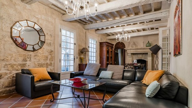 Una sala de estar con un sofá modular, dos sillones, una mesa de centro de vidrio y un espejo grande en la pared.