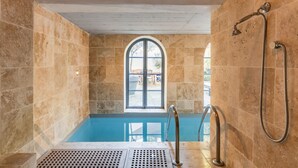 Un jacuzzi con vistas al exterior, paredes de piedra y zona de ducha.