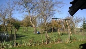 Un espace extérieur clôturé, agrémenté d’arbres et d’une balançoire.