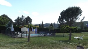 A backyard with a swimming pool, lounge chairs, and a small building with blue doors. - Spacious villa, private, secure swimming pool Jacuzzi on large, enclosed grounds (Sampzon)