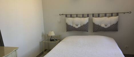 A bedroom with a bed, a nightstand with a lamp, and two wall-mounted light fixtures.