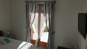 A bedroom with a bed, a chair, a TV, and a window with curtains. - Spacious villa, private, secure swimming pool Jacuzzi on large, enclosed grounds (Sampzon)