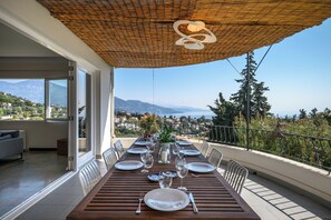 A dining table set for six on a balcony with a view of mountains and a town. - Magnificent Provencal Villa with swimming pool, sea view, near Monaco and Italy (Roquebrune-Cap-Martin)