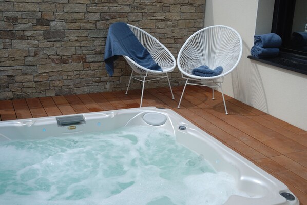 A hot tub with two white chairs, a stone wall, and a window with towels. - Brittany Port Goret: house seaside 4 * 500m sea / GR34, jaccuzi (Tréveneuc)