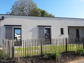 A modern building with a grey facade, a wooden fence, and a grassy yard. - Brittany Port Goret: house seaside 4 * 500m sea / GR34, jaccuzi (Tréveneuc)