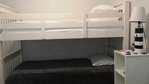 A bunk bed room with a small bedside table and a lamp.