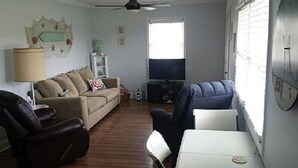 A living room with a sofa, a chair, a television, and a table.
