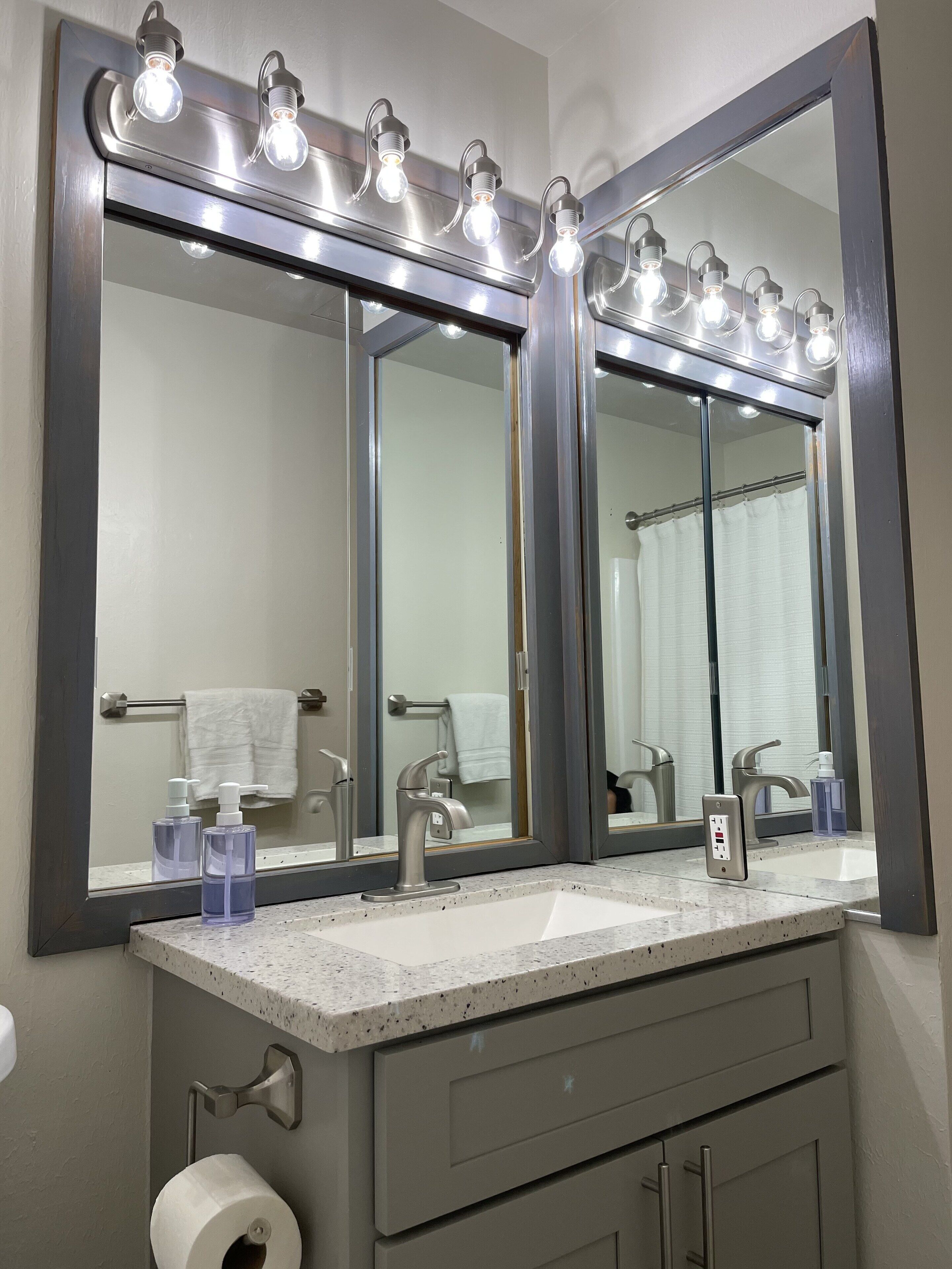 Une salle de bain avec un grand miroir, un meuble-lavabo et un porte-serviettes.