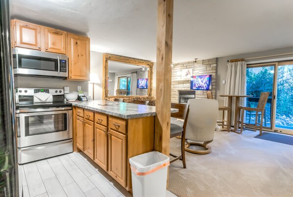 A modern kitchen with wooden cabinets, stainless steel appliances, and a large mirror.