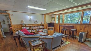 A cozy living room with a sofa, armchairs, a coffee table, a bookshelf, and a television. - Your Lakeside Paradise: A/C, Private Dock, Kayaks & Rowboat on Dexter Pond! (Wayne)