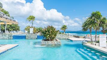 Une piscine à l’eau d’un bleu cristallin, entourée de murs de pierre et de palmiers.