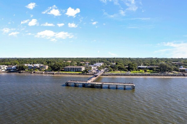 A waterfront property with a pier extending into the water, surrounded by residential buildings and greenery.