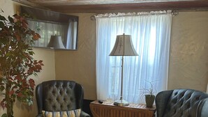 Uma sala de estar com dois poltronas de couro, uma mesa de centro de madeira, um abajur e um vaso com planta.