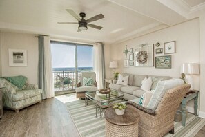 Ein geräumiges Wohnzimmer mit Balkon, Deckenventilator und Meerblick.