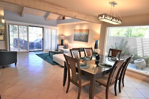 A spacious dining area with a large table and chairs, a sofa, and a coffee table in the background.