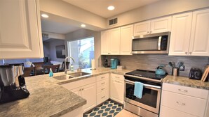 A modern kitchen with white cabinets, a stainless steel stove, and a microwave.