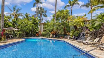 A swimming pool with lounge chairs and palm trees.