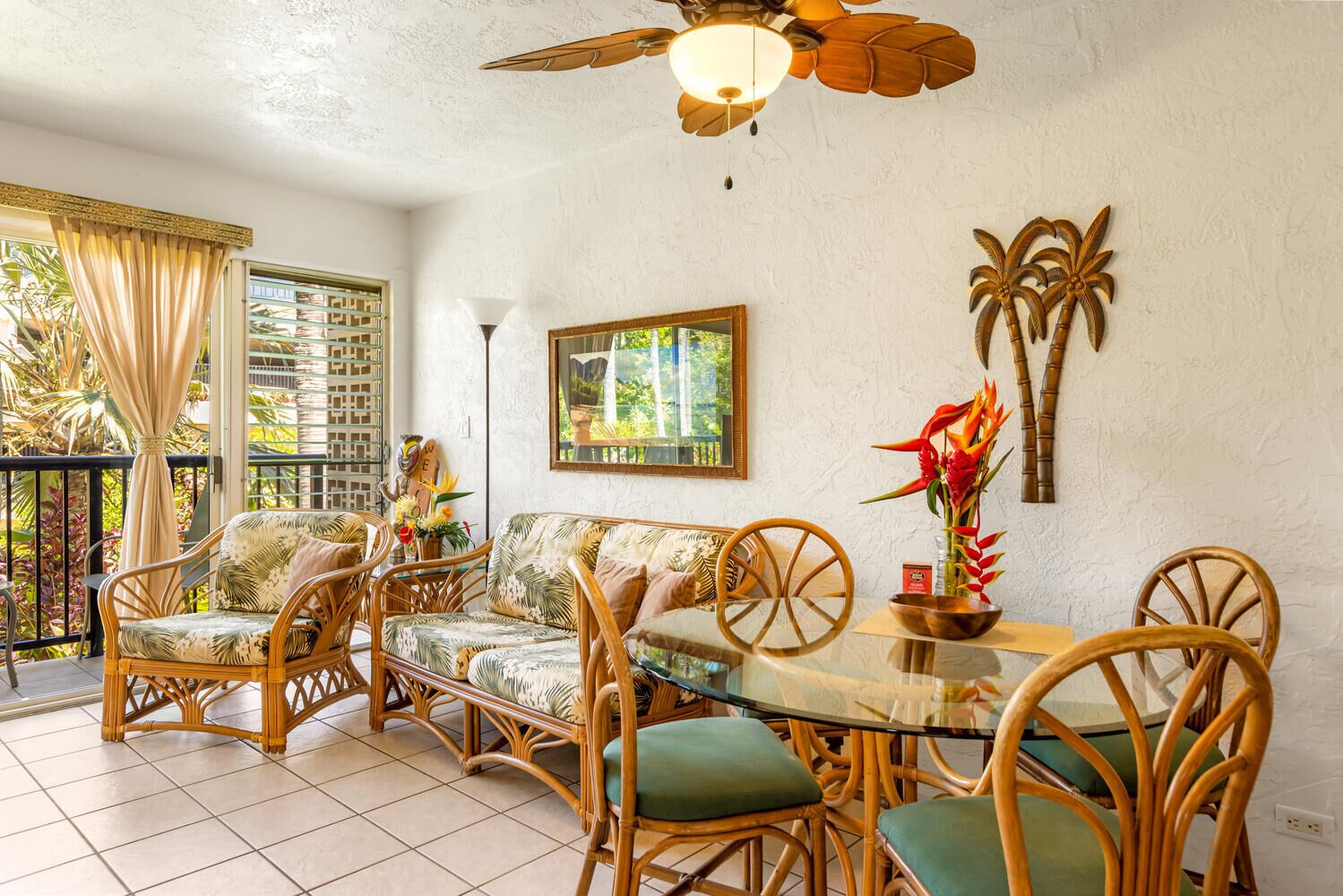 A dining area with wicker furniture, a glass table, and a ceiling fan.