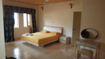 Une chambre à coucher comprenant un lit, des tables de chevet, une commode, un miroir et un ventilateur de plafond.
