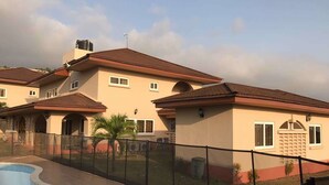 A residential complex with multiple houses, a swimming pool, and a fenced yard. - The Villa 9 at Seaview Estate (Freetown)