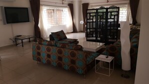 A living room with a sofa set, a TV, a table, and a decorative screen. - The Villa 9 at Seaview Estate (Freetown)