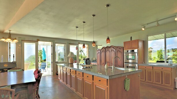 A spacious kitchen with a large island, wooden cabinets, and pendant lighting. - Puumoi Pink House, 3 bedroom home with sunrise and ocean view.10 minutes to Hilo (Papaikou)