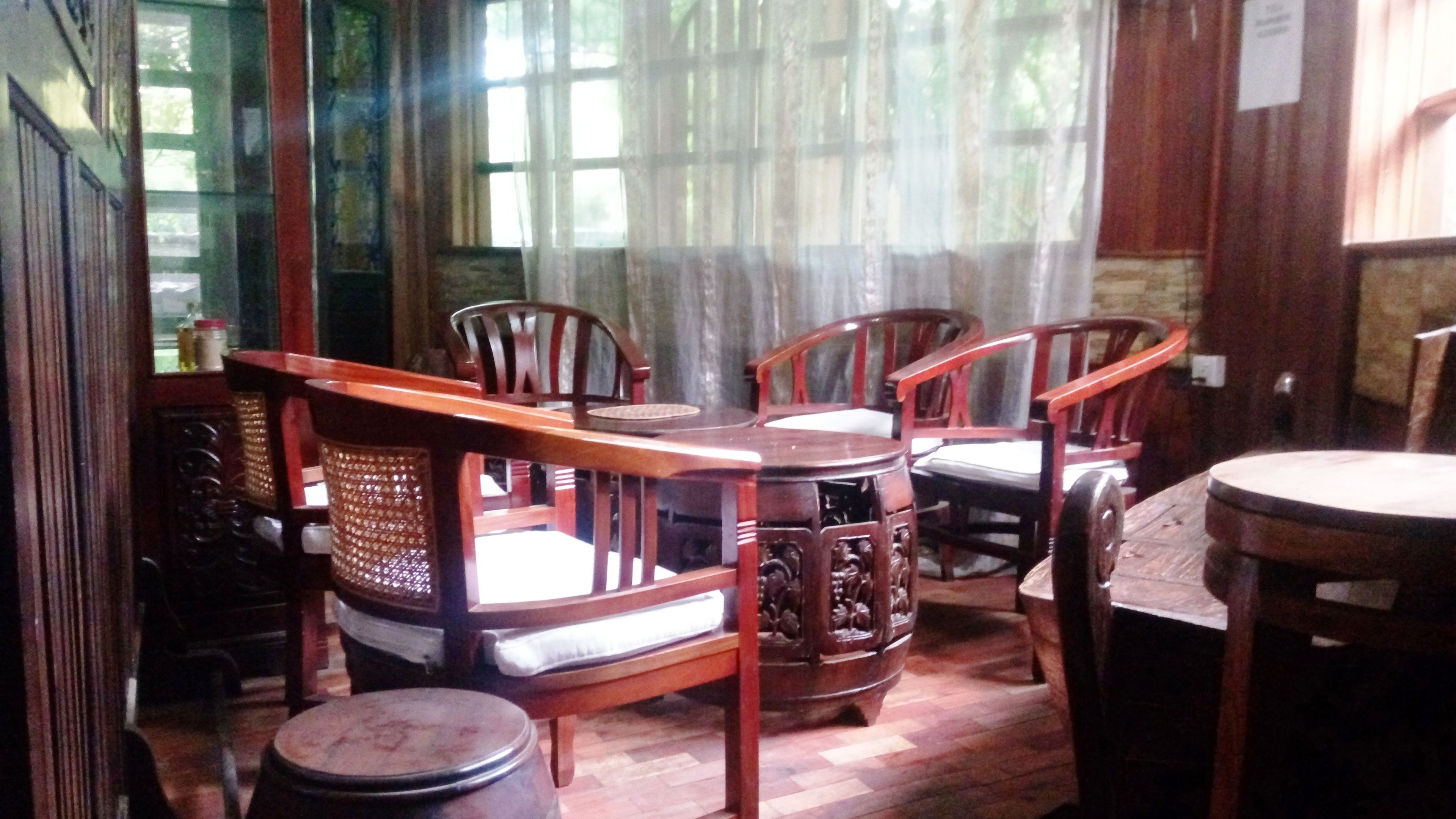 Uma área de jantar tradicional em madeira, com cadeiras, uma mesa, uma cesta de vime e um banquinho de madeira redondo.