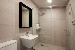 Une salle de bain moderne avec une douche à parois de verre, un lavabo blanc et des toilettes.