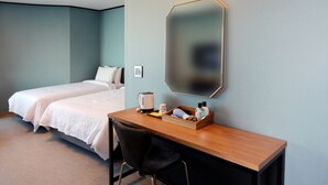 Een hotelkamer met twee bedden, een houten bureau, een stoel, een spiegel en een klein tafeltje met toiletartikelen.