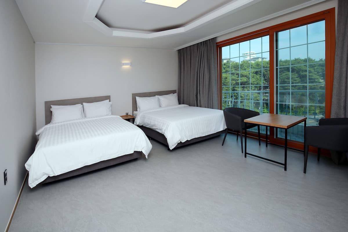 Een moderne hotelkamer met twee bedden, een tafeltje en een stoel.