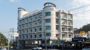 Een hotel met meerdere verdiepingen, balkons, een centrale cilindervormige toren en borden voor een koffietent.
