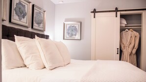 Une chambre à coucher avec un lit, des oreillers, une armoire et des œuvres d’art encadrées accrochées au mur.