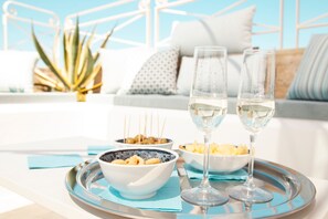 A tray with two glasses of white wine, bowls of snacks, and a plant in a hotel room. - Dimora Maio (Monopoli)
