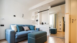 Una sala moderna con un sofá azul, un reposapiés a juego y un espejo grande que refleja la habitación.