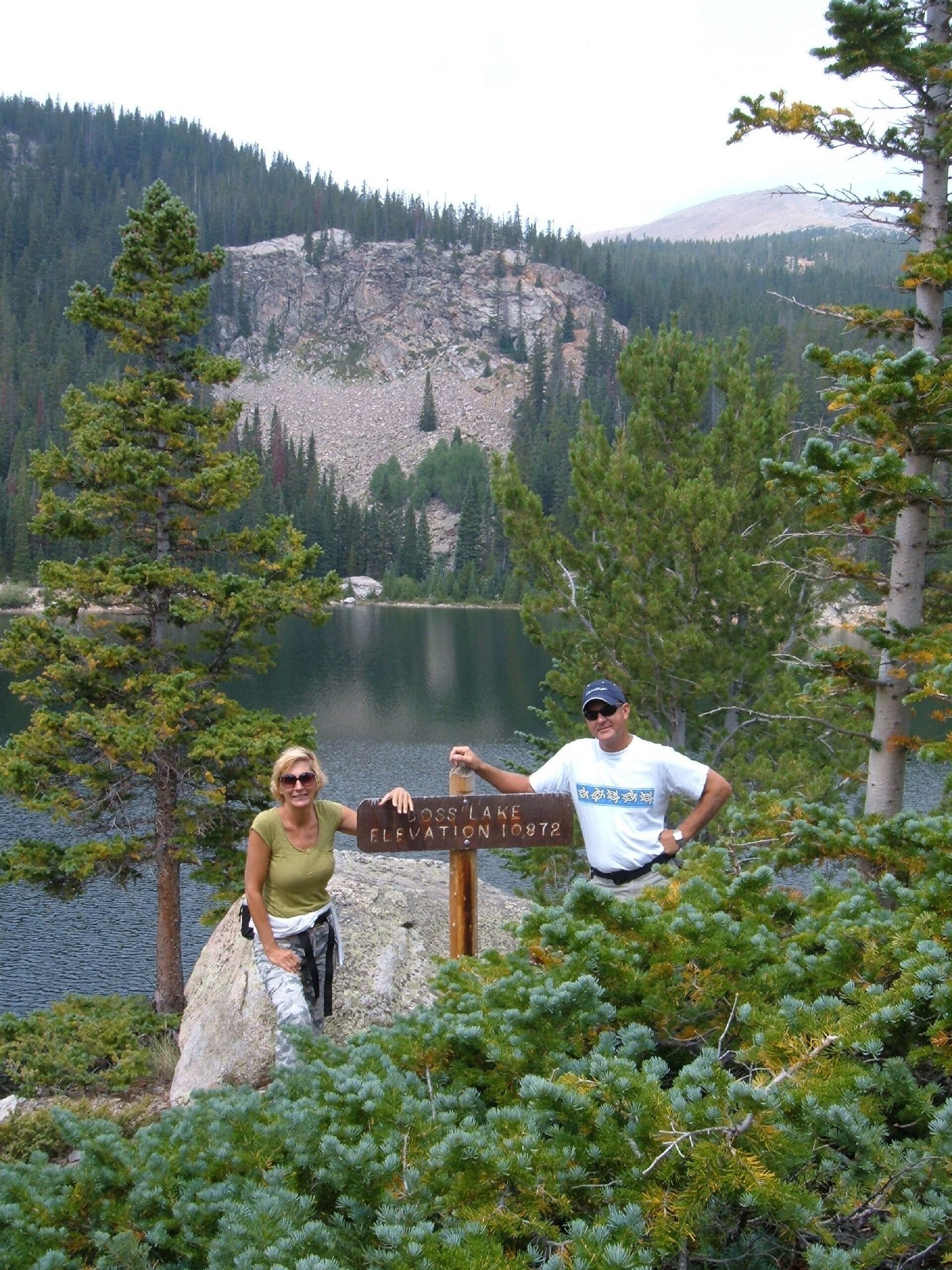 Un panneau indicateur portant l’inscription « LOSS LAKE ELEVATION 10872 », placé dans un environnement naturel avec un lac et des montagnes en arrière-plan.