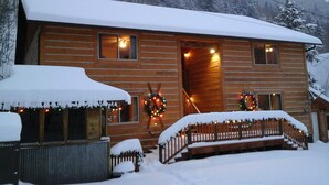 A log cabin with a snow-covered roof and front porch, decorated with Christmas lights and wreaths. - Ski Town Condos - Mountain Comfort in Monarch/Garfield, Colorado (Salida)