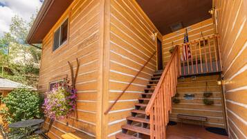 Une cabane en bois avec un escalier en bois menant à une terrasse.