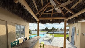 A covered patio with a pool, outdoor seating, and a view of the pool area.